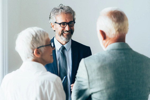 Two men and a woman, all in business attire, having a discussion in an office