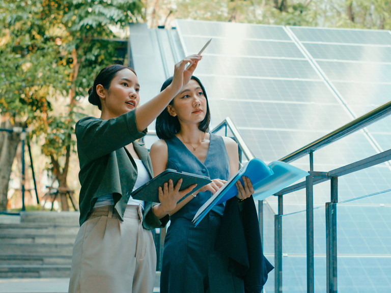 two people working outdoors with solar panels in the background