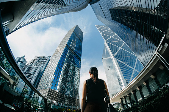 businessperson in city looking out at multiple buildings
